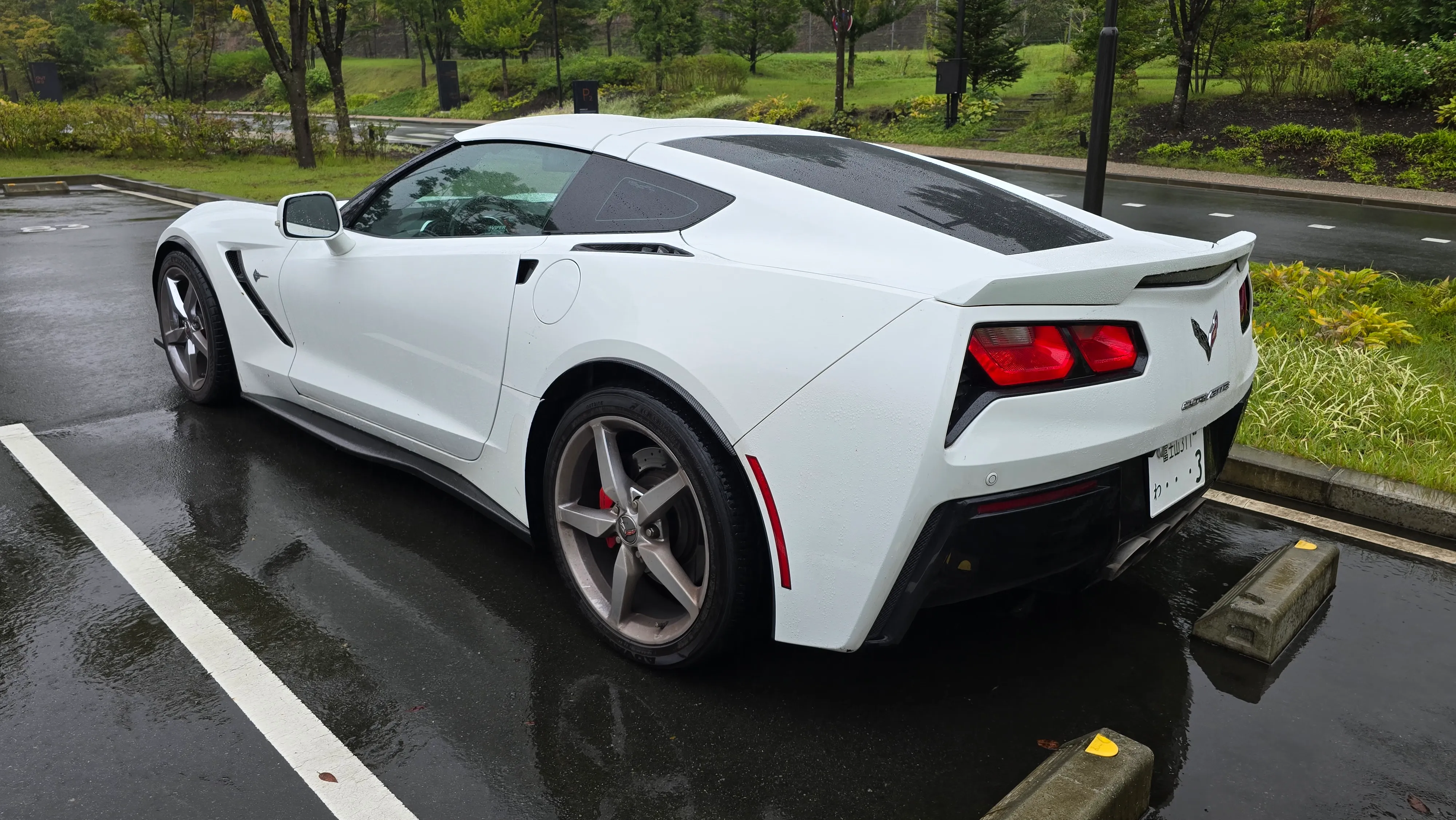 Corvette C7 Stingray blanche garée sur le parking gratuit du musée, sous la pluie