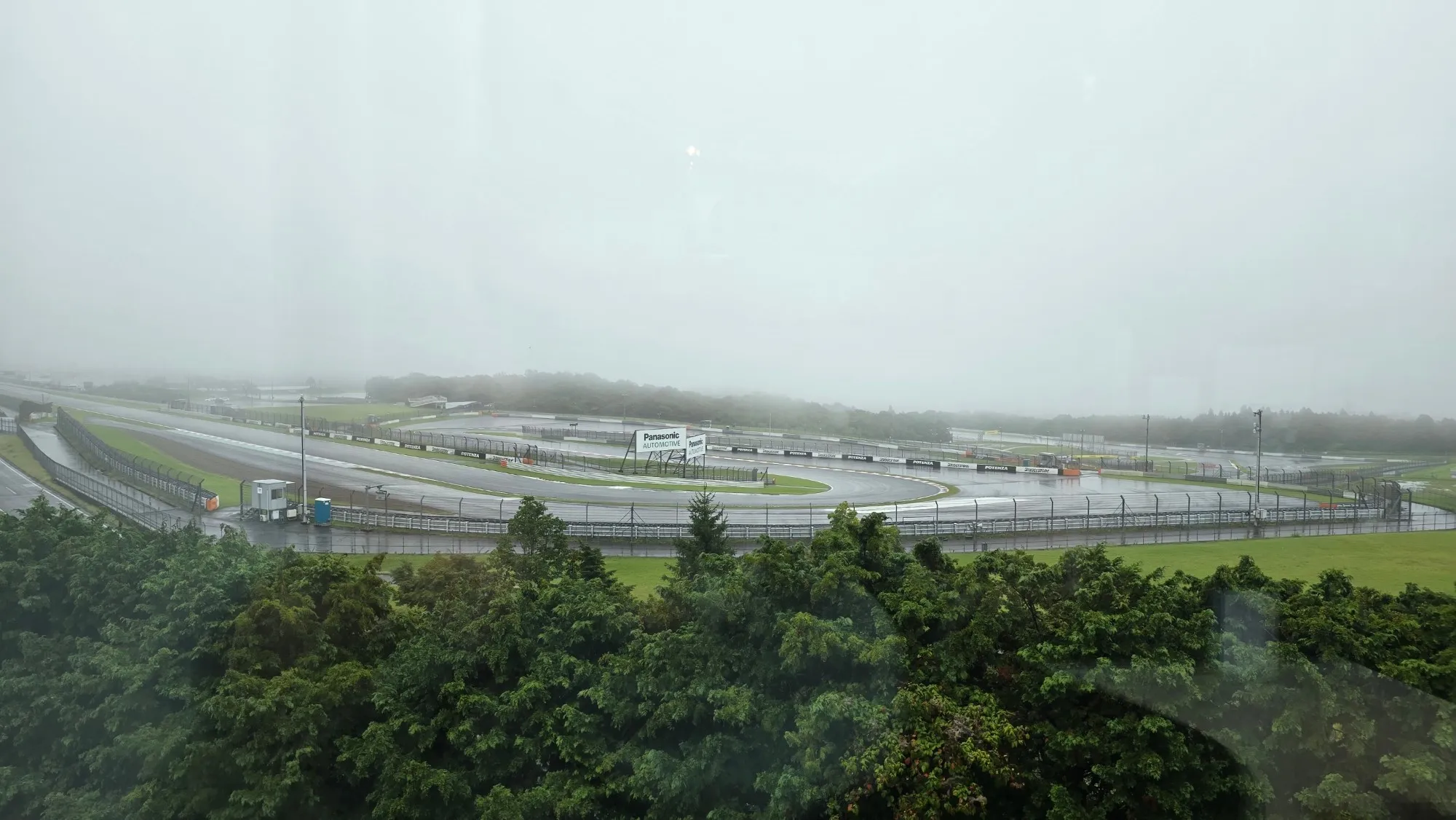 Vue du circuit de Fuji Speedway dans le brouillard, virage et panneaux Panasonic Automotive visibles