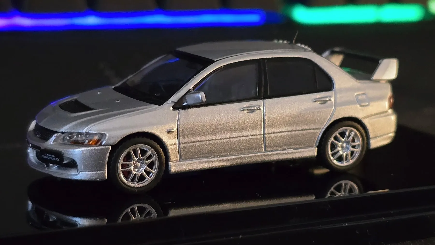 Miniature d'une Mitsubishi Lancer Evolution IX gris argent au 1/64 sur son socle noir