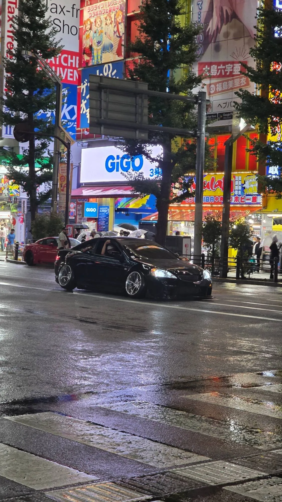 Coupé japonais widebody noir sous la pluie à Akihabara